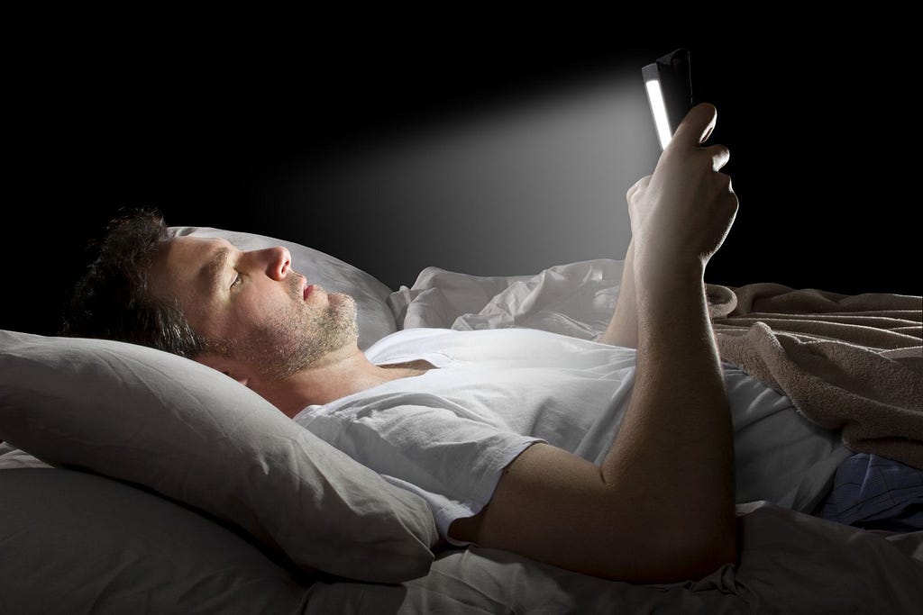 man in bed exposed to blue light